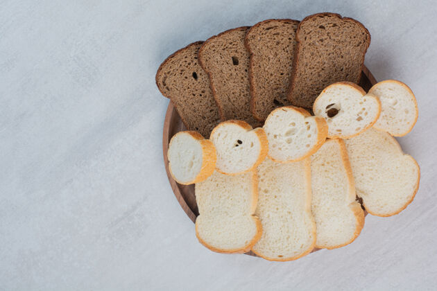 切片新鲜的白色和棕色面包片放在大理石背景上白色新鲜糕点