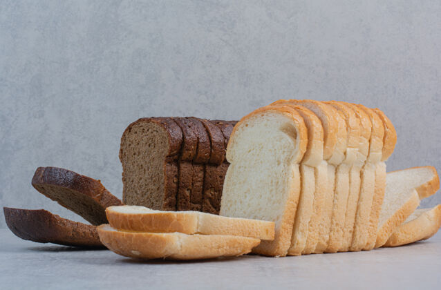 切片新鲜的白色和棕色面包片放在大理石背景上白色小吃烘焙