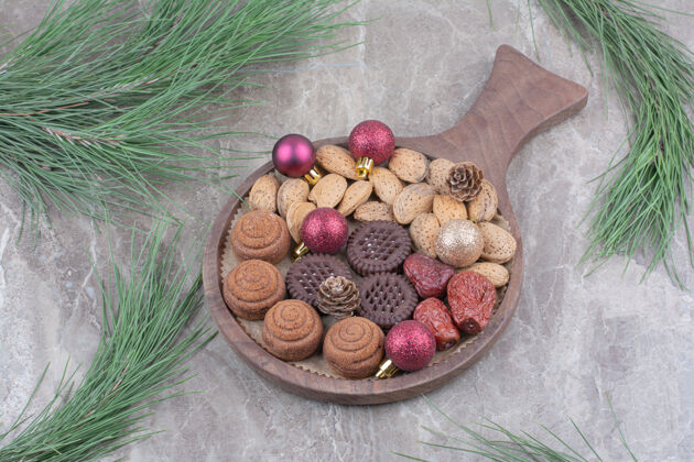 杏仁大理石背景上放着杏仁和饼干的木板圣诞球面包房糕点