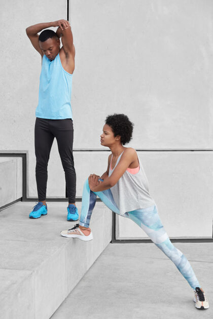 体操非洲裔美国男性成年人举手 在有氧训练前热身穿着紧身裤和运动鞋的黑皮肤女性伸展双腿 准备慢跑马拉松两个运动型的人在楼梯上柔韧站立观点