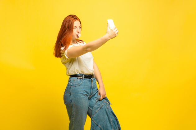 事业更容易成为追随者自拍需要最少的衣服黄色背景上的白人女性肖像漂亮的女性红发模特人类情感的概念 面部表情 销售 广告人成功影响者