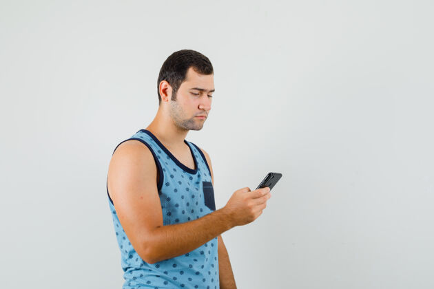 手机年轻人用手机在蓝色的单打 看起来很忙前视图时尚肖像聪明