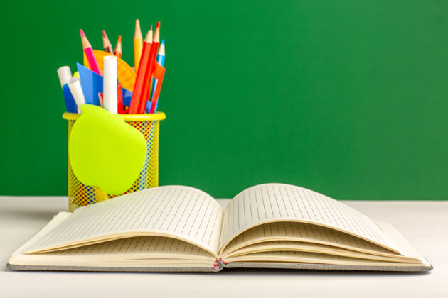 书籍前视图彩色铅笔与复写本上的绿色表面多彩羽毛球正面