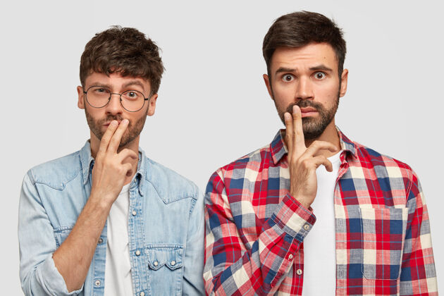 团队横观两位留胡须的男生表情严肃体贴 手指捂着嘴 想方设法解决问题 解决问题 做项目 穿休闲服 站在室内思想年轻胡茬