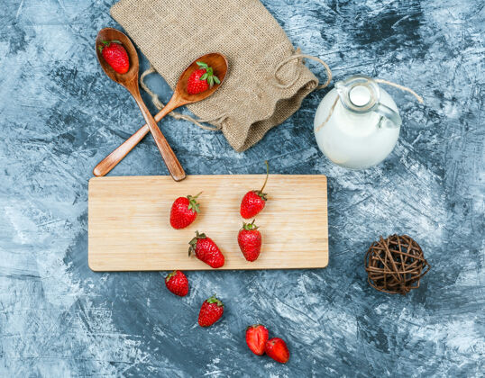 活力俯视图草莓与牛奶 提示 木勺和一个深蓝色大理石表面上的一块麻袋砧板水平板种子大理石