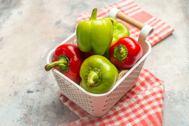 青椒和红椒顶视图绿色和红色辣椒在塑料篮红白格子桌布裸体表面顶部方格青椒
