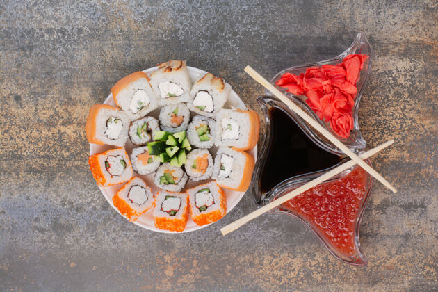 五颜六色一套美味的寿司 用筷子和姜放在大理石表面卷多汁的三文鱼