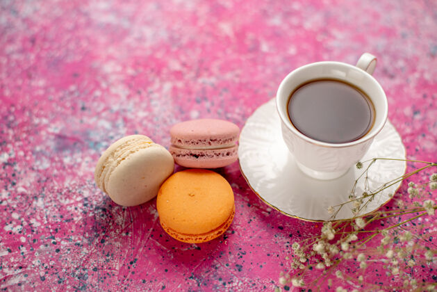 饮料正面图：茶杯放在盘子里 粉色桌子上放着法国马卡龙正面早餐法式