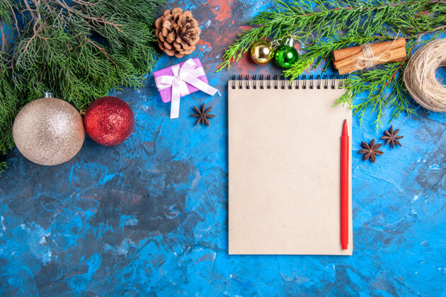 顶部顶视图红色铅笔笔记本松树上的蓝色树枝表面与自由空间圣诞节树枝花