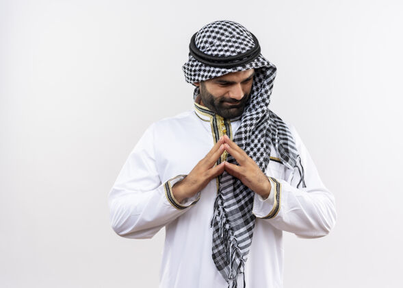 在一起身着传统服装的阿拉伯男子双手合十 面带微笑 站在白色的墙壁上站在一边男人