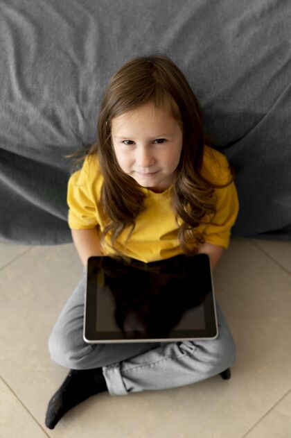 孩子高角度的小女孩用平板电脑垂直年轻人消遣