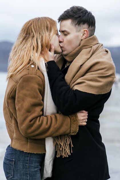 男人冬季户外接吻的年轻情侣侧视图旅行户外冒险
