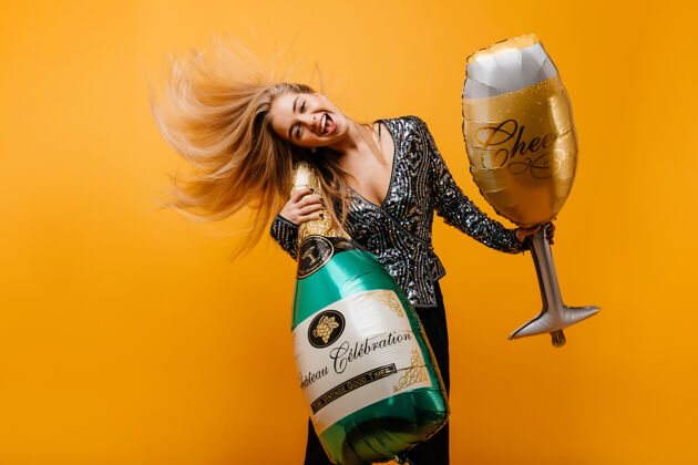 优雅兴奋的生日女人拿着一瓶香槟跳舞积极的情感女人在派对后鬼混的画像节日派对模特