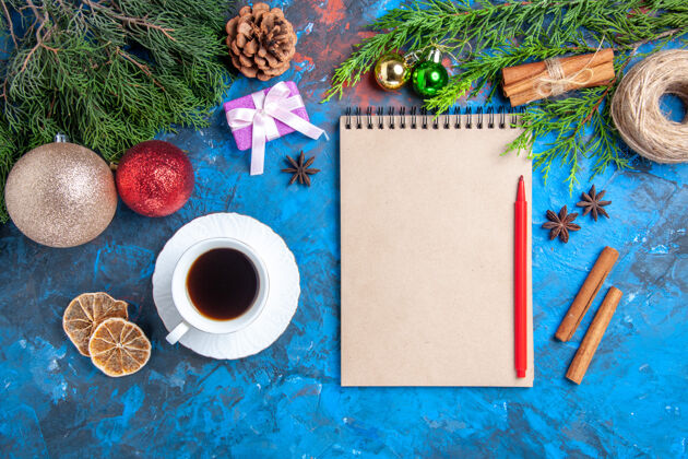 视图顶视图笔记本上的红铅笔松树枝上的一杯茶在蓝色的表面铅笔叶庇护所