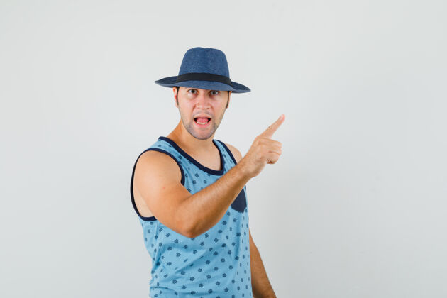 男人年轻人用手指在蓝色的单打警告 帽子和愤怒的样子前视图前面男性年轻