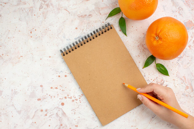 柑橘顶视图新鲜的橙子一个笔记本铅笔在女性手上明亮的表面自由的地方柑橘视图铅笔