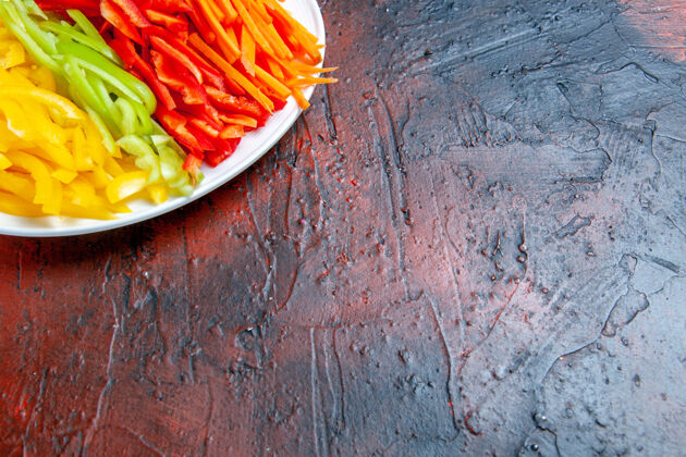 碗上半部分查看彩色切辣椒在白色盘子上的暗红色桌子与自由的地方辣椒午餐地方