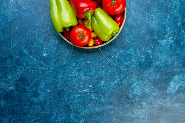 顶部上半视图蔬菜樱桃西红柿不同颜色的甜椒西红柿在碗里蓝色的桌子上复制的地方观点铃铛甜椒