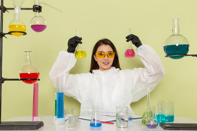 溶液正面图身着特殊防护服的女化学家在绿色表面上微笑着处理溶液实验室正面科学
