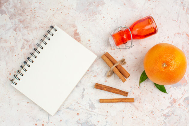 笔记本顶视图新鲜的橙色肉桂棒瓶笔记本在明亮的表面鲜橙明亮利器