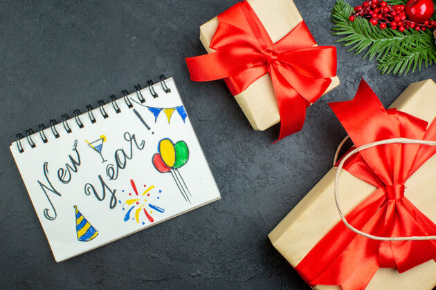 轮子上图是圣诞气氛与美丽的礼物和冷杉枝针叶树锥旁边的笔记本在黑暗的背景针叶树蝴蝶结心情