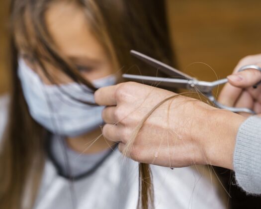 女人戴着医用口罩理发的小女孩发型师女剪刀