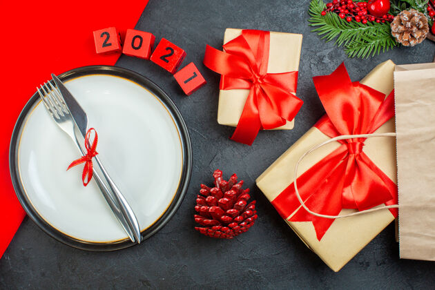 蝴蝶结上图中美丽的礼物和餐具摆放在一个板上针叶树圆锥形冷杉树枝上 数字在黑暗的背景上餐具圣诞号码