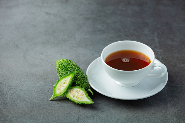 饮食一杯热苦瓜茶和生苦瓜片放在黑暗的地板上健康替代品中国