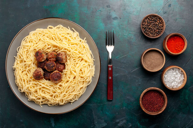 烹饪顶视图煮熟的意大利面食与肉丸和调味品在深蓝色的表面酱汁肉食物