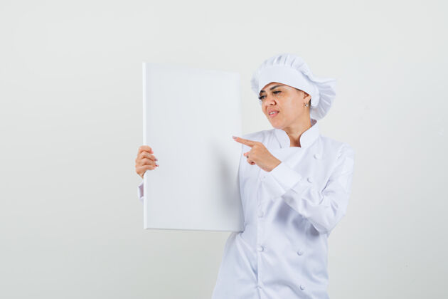 工业女厨师指着白色制服的空白画布餐厅厨师亚洲