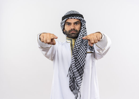 手指身着传统服装的阿拉伯男子自信地站在白墙上指指点点阿拉伯语看自信