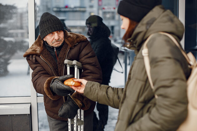 户外在一个冬天的城市里无家可归有人要食物手女人男性