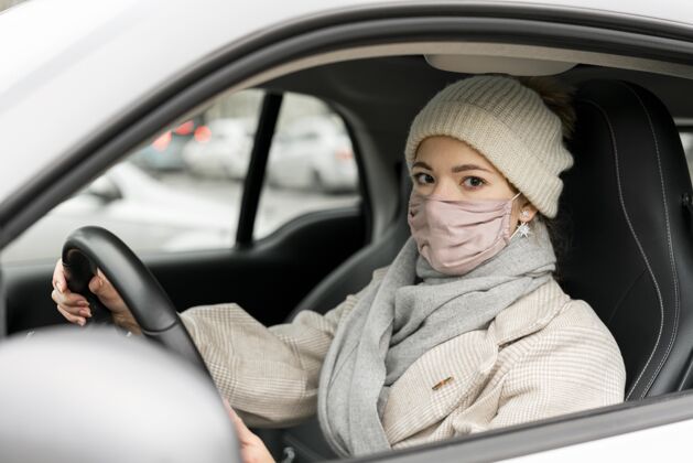 冠状病毒戴着医用面罩开车的女士侧视图公民个人病毒