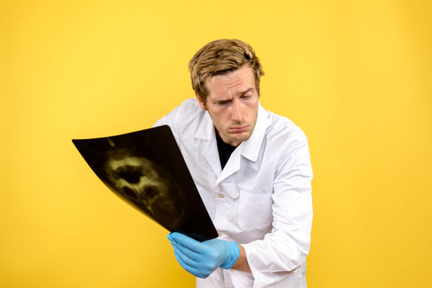 外科正面图：黄色桌子上拿着x光片的男医生 医疗科维德-卫生外科前面成功医生