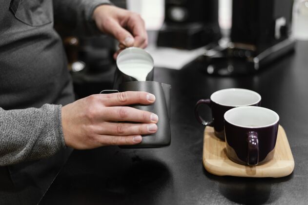 专业男咖啡师围着围裙给咖啡杯倒泡沫牛奶职业咖啡师咖啡馆