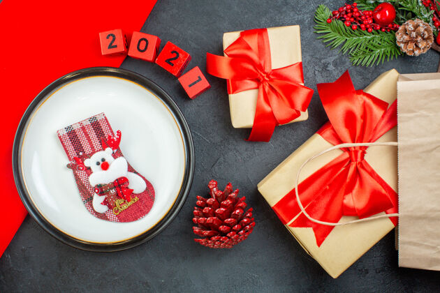 蝴蝶结上图：圣诞袜放在一张黑色的桌子上 上面是针叶树 圆锥形杉木 树枝 数字 美丽的礼物针叶树视图包装