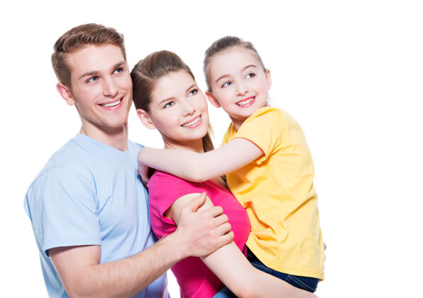 看一个幸福的年轻家庭的肖像 孩子穿着五彩衬衫-隔离在白墙上快乐拥抱牙齿
