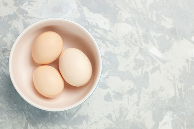 盘子顶上近距离观察浅白色桌子上的小盘子里的生鸡蛋晚餐封闭早上