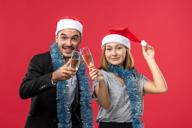 圣诞节正面图红墙上庆祝新年的年轻夫妇爱圣诞派对饮料帽子风景成人
