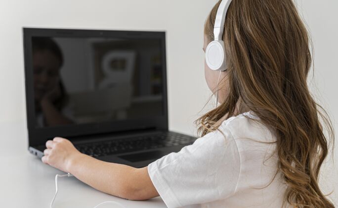 水平女孩使用带耳机的笔记本电脑的侧视图娱乐设备科技