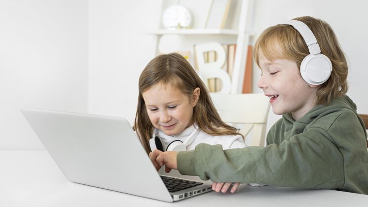 消遣年轻的男孩和女孩使用带耳机的笔记本电脑娱乐年轻孩子