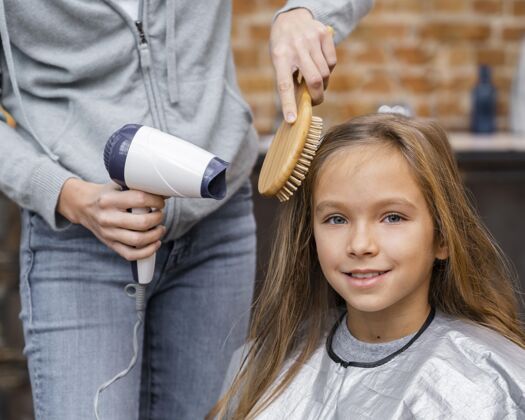理发师小女孩正在梳头和吹干头发理发孩子水平