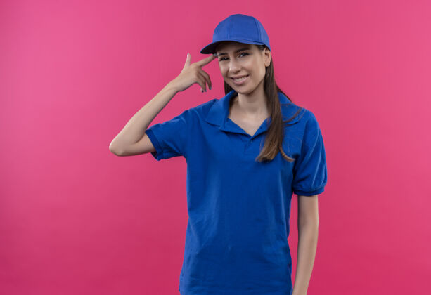 年轻穿着蓝色制服 戴着帽子的年轻女送货员困惑地指着太阳穴说错话指蓝色帽子