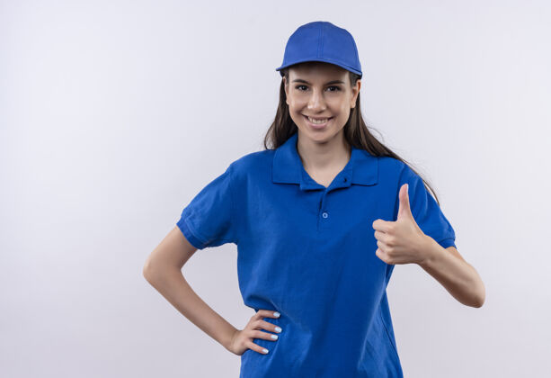 蓝色身着蓝色制服 头戴帽子的年轻送货员看着摄像机 兴高采烈地竖起大拇指拇指交货女孩