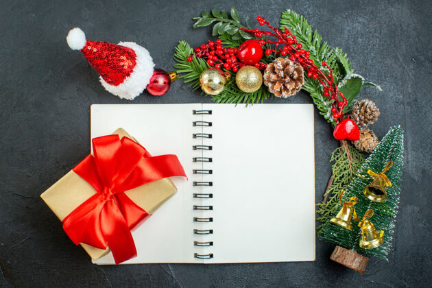 蝴蝶结顶视图圣诞心情与杉木树枝圣诞老人帽子圣诞树礼品盒笔记本上的黑暗背景笔记本季节视图