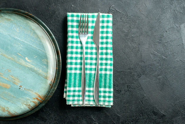 刀上半部分查看圆形拼盘晚餐刀叉上的绿色和白色方格餐巾上的黑色桌子复制的地方量杯针餐巾