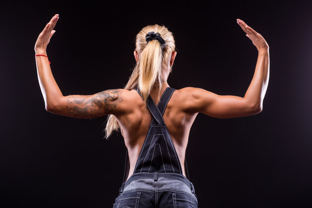 运动一个美丽的运动女子在黑暗中的肖像后视图私人教练体重训练