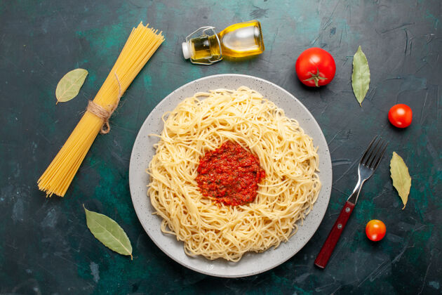 桌子在深蓝色的桌子上俯瞰着意大利面和番茄肉末晚餐西红柿午餐