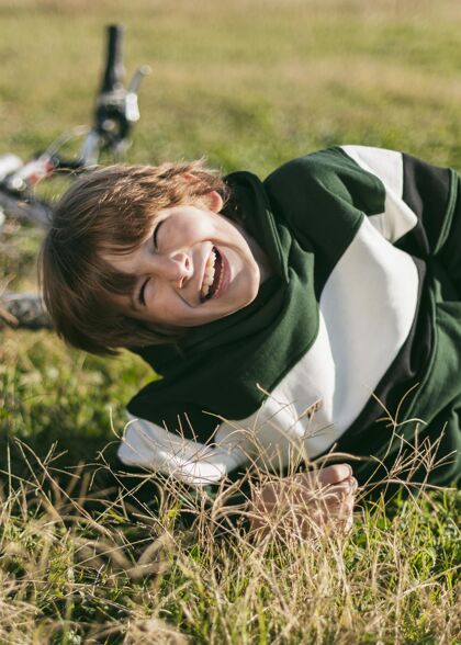 户外笑脸男孩骑着自行车在草地上放松年轻户外活跃