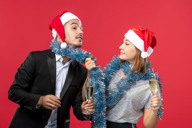 年轻夫妇正面图：年轻夫妇在红桌上庆祝新年 爱的圣诞派对饮料书桌美丽风景